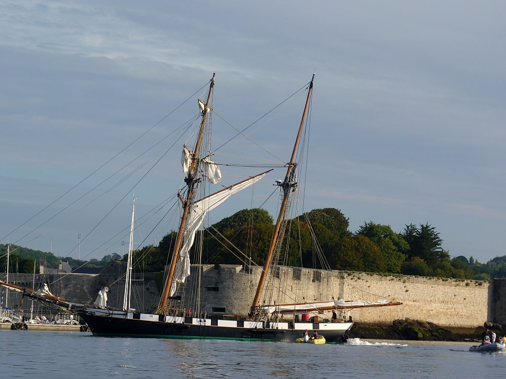 Rempart de Concarneau dans le Finistère  en fond avec un beau voilier en bois noir et blanc sur la mer