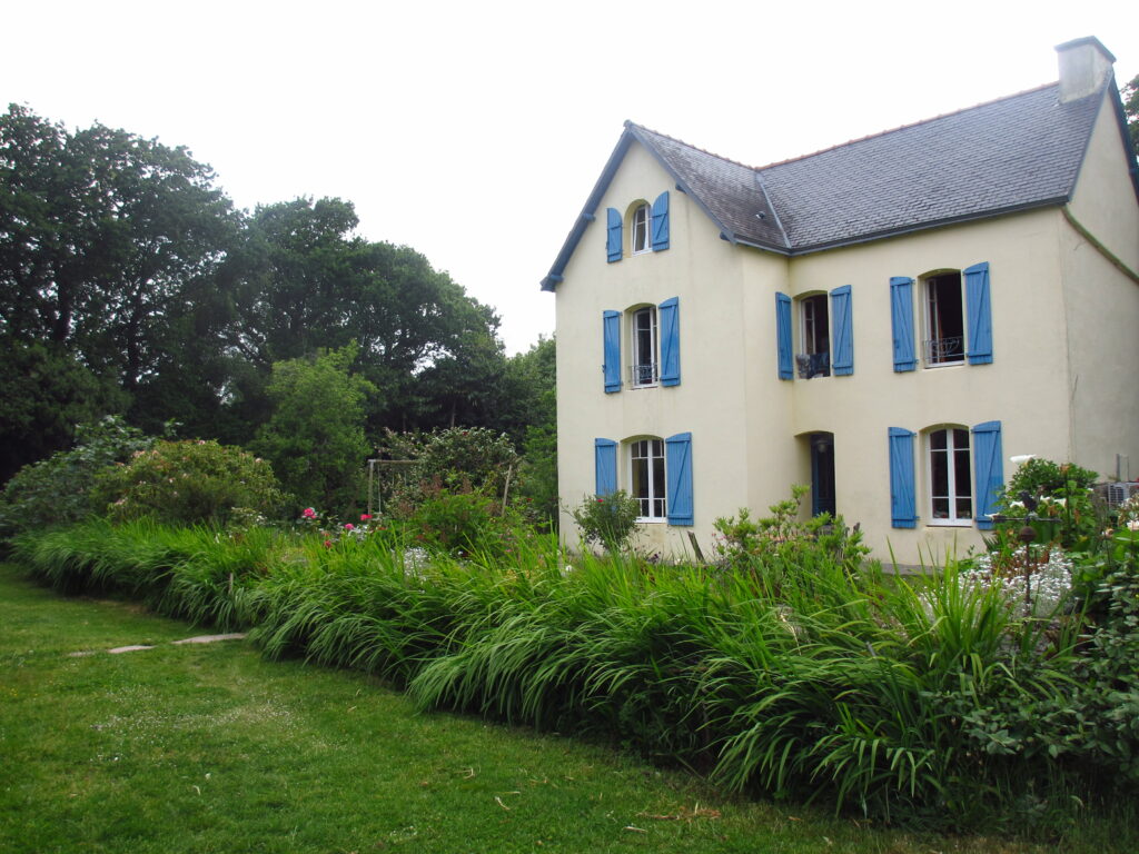 Maison jaune avec les volets bleus de Melgven et le jardin devant 