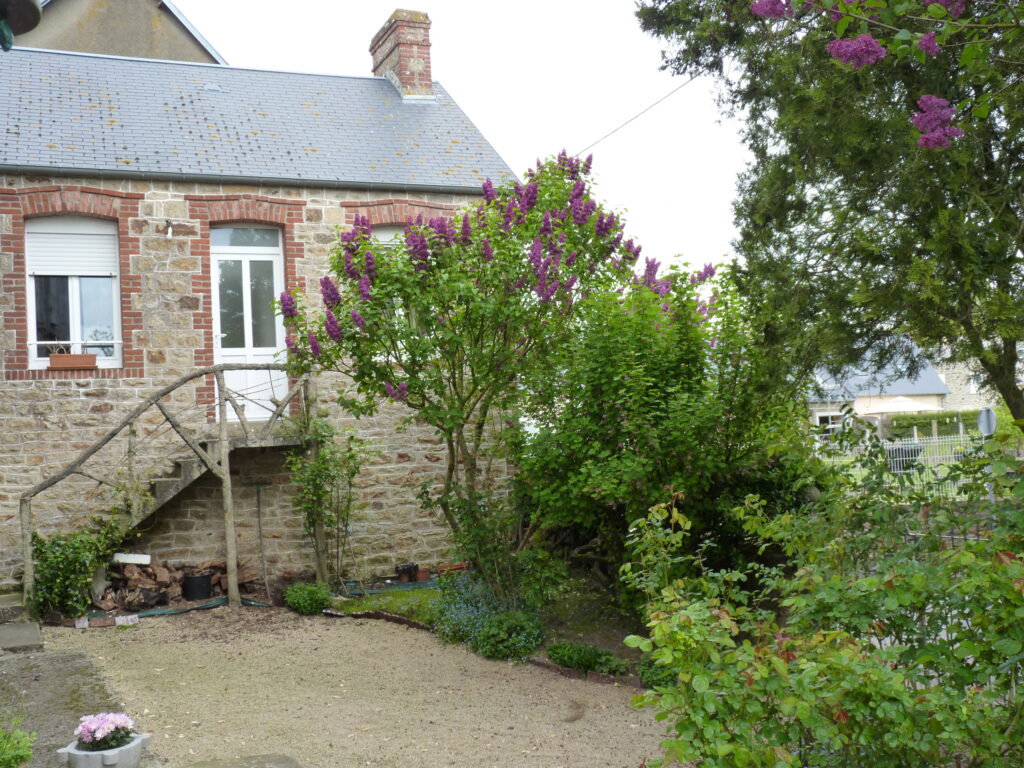 Gîte Genêt avec façade en pierres et le  lilas fleuri violet