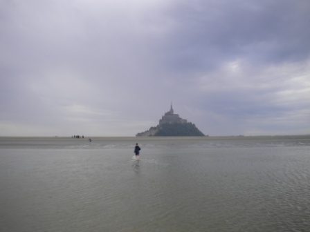 Mont saint Michel en  arrière plan et silouette d'une personne traversant la Baie