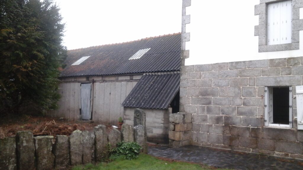 aperçu e la façade de la maison avec ses pierres de granits en bas et le haut le crépi blac. On voit aussi l'ancienne étable en pierres debouts et la séparation entre les 2 maisons en pierres debouts également.