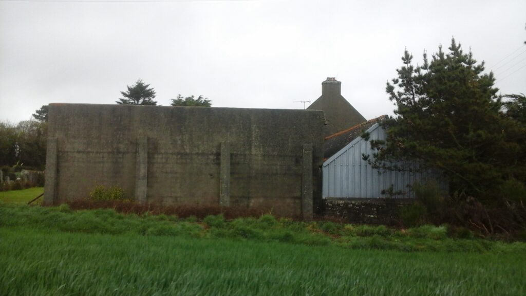 Mur de l'ancienne porcherie en béton et contrefort également en béton